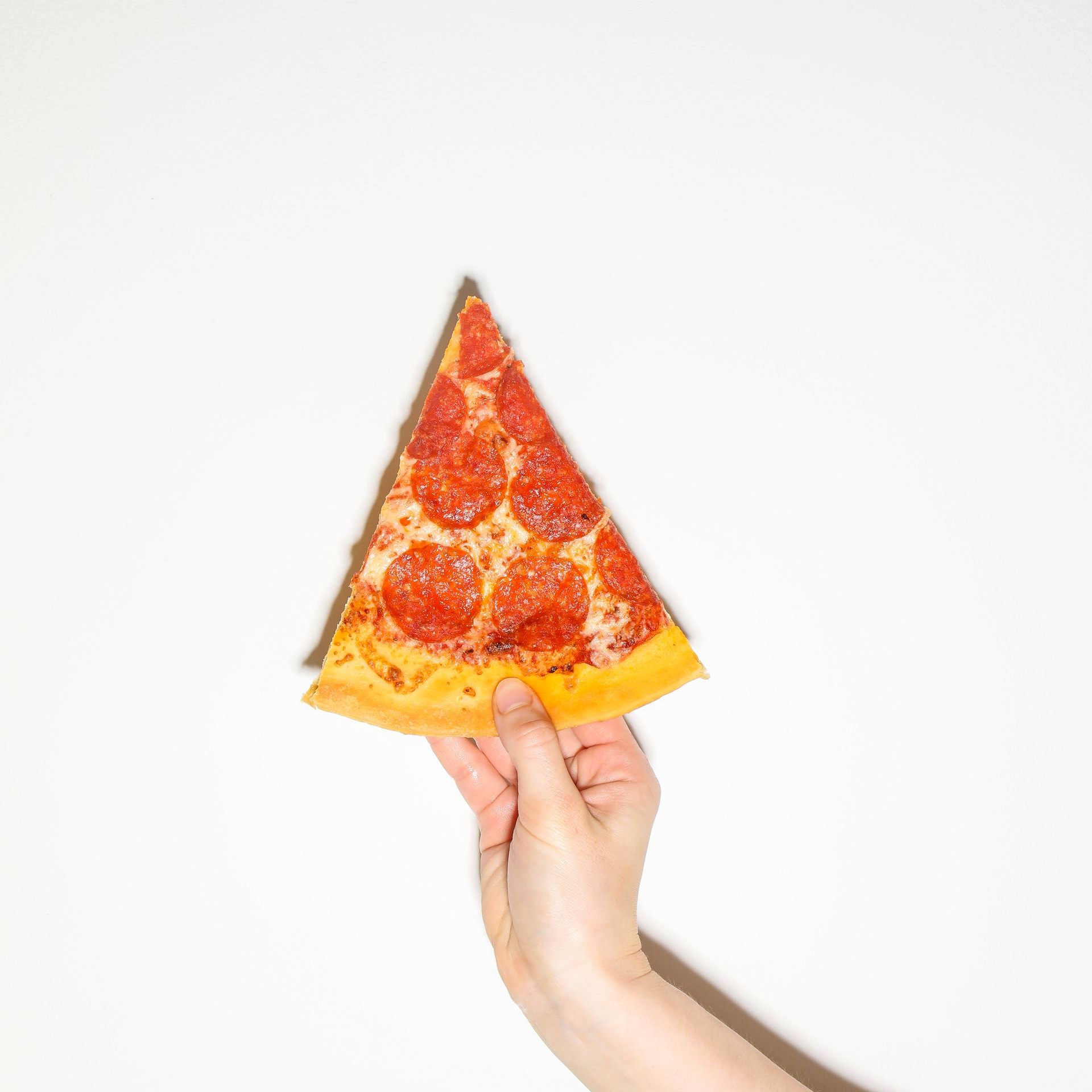 Menu — Pizza A slice of pizza held against a white background