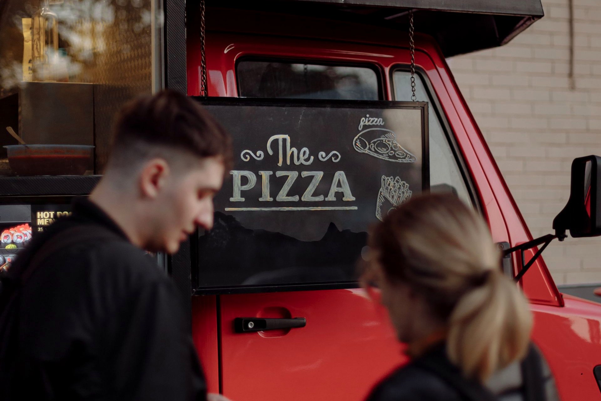 A red pizza van serving customers
